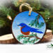 A handmade Christmas ornament with an eastern bluebird hand-painted on a wood slice at Cove Creek Photography.